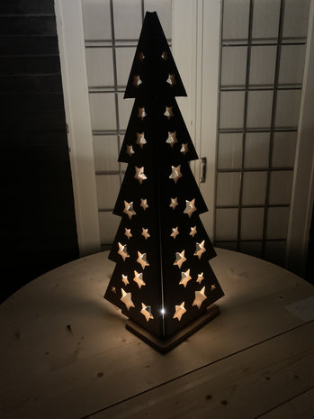 Kerstboom met sterren in een hoek met een lichtje er achter